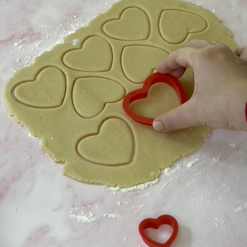 cortando la masa de galletas con cortador en forma de corazón