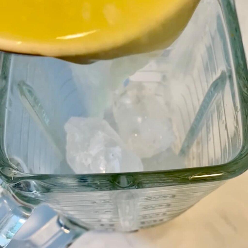 colocando hielo y jugo de limon en la licuadora